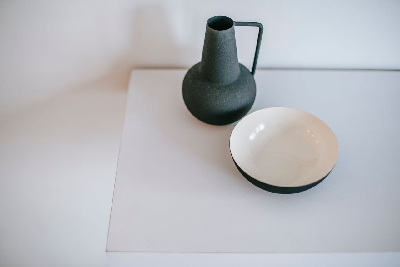 Services-01 Viewed from above: an empty vase with a handle beside a round bowl on a white desk at home